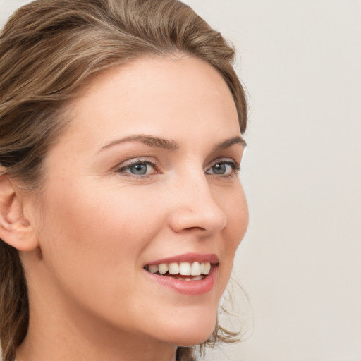 Joyful white young-adult female with medium  brown hair and grey eyes