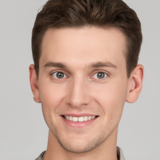 Joyful white young-adult male with short  brown hair and grey eyes