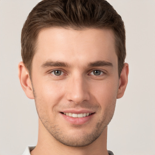 Joyful white young-adult male with short  brown hair and grey eyes