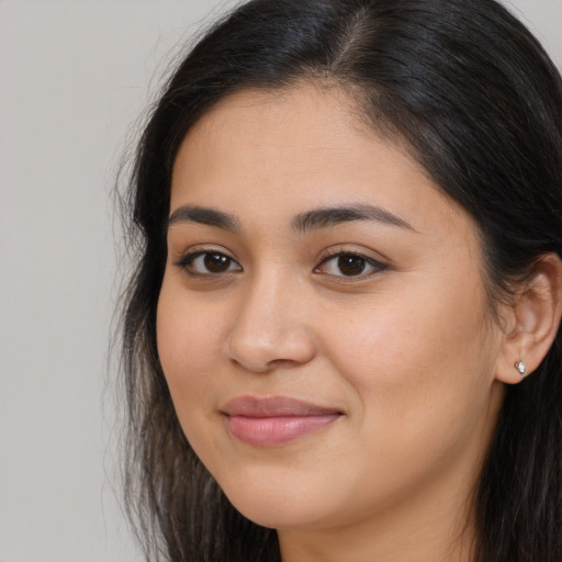 Joyful latino young-adult female with long  brown hair and brown eyes