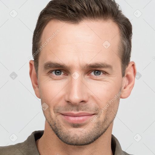 Joyful white young-adult male with short  brown hair and grey eyes