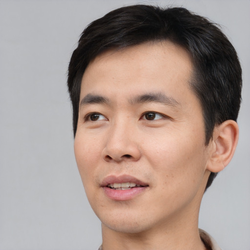 Joyful asian young-adult male with short  black hair and brown eyes