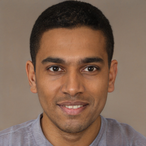 Joyful black young-adult male with short  brown hair and brown eyes