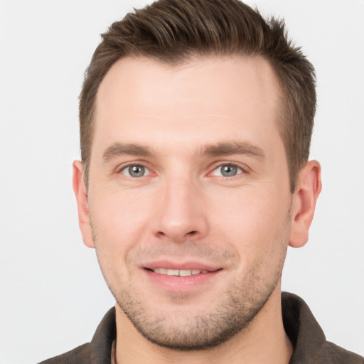 Joyful white young-adult male with short  brown hair and grey eyes