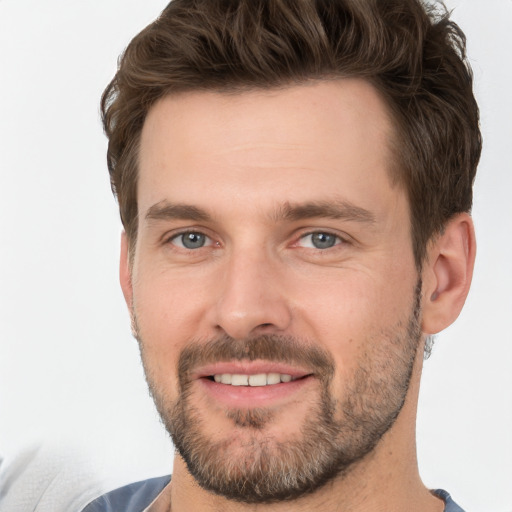 Joyful white young-adult male with short  brown hair and grey eyes