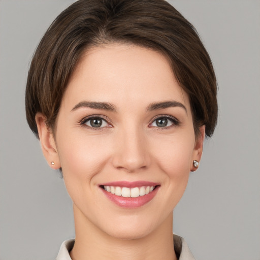 Joyful white young-adult female with short  brown hair and grey eyes