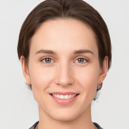 Joyful white young-adult female with medium  brown hair and grey eyes