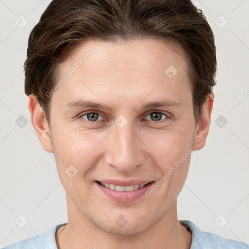 Joyful white young-adult male with short  brown hair and grey eyes