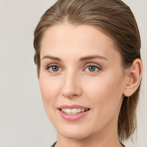 Joyful white young-adult female with medium  brown hair and grey eyes