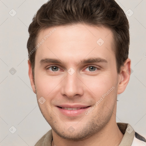 Joyful white young-adult male with short  brown hair and grey eyes