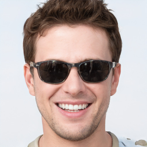 Joyful white young-adult male with short  brown hair and blue eyes