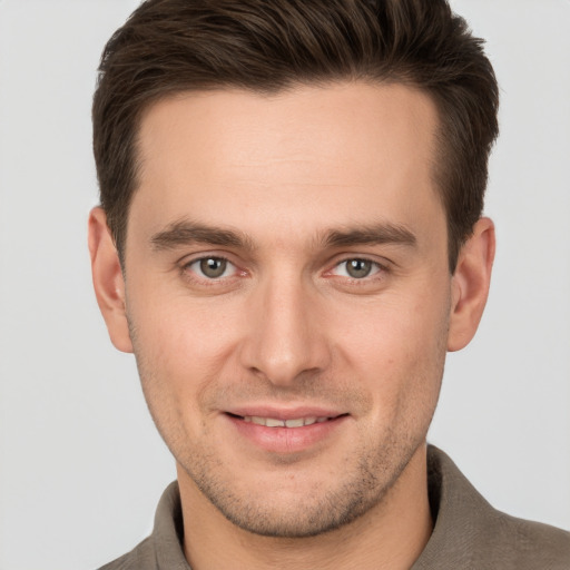 Joyful white young-adult male with short  brown hair and grey eyes