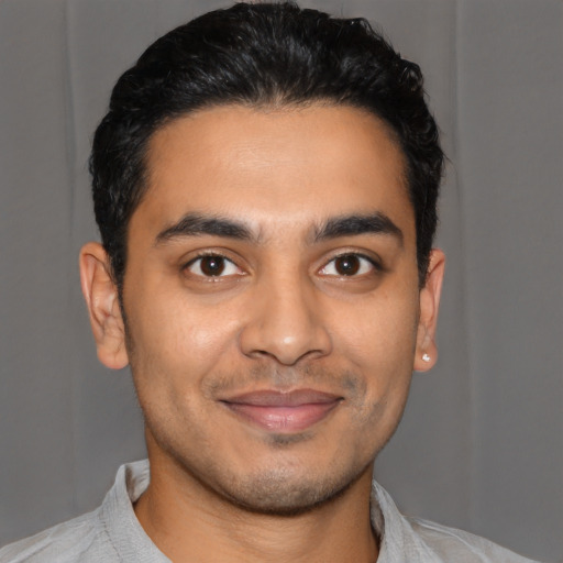 Joyful latino young-adult male with short  black hair and brown eyes