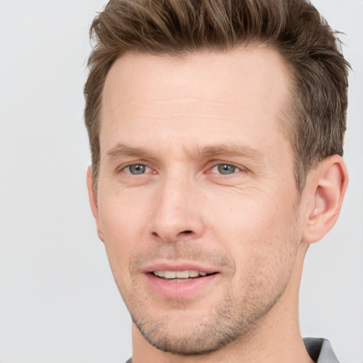 Joyful white young-adult male with short  brown hair and grey eyes