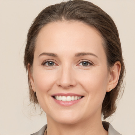 Joyful white young-adult female with medium  brown hair and grey eyes