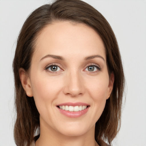 Joyful white young-adult female with medium  brown hair and grey eyes