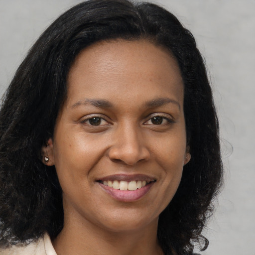Joyful black young-adult female with long  brown hair and brown eyes