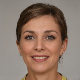 Joyful white young-adult female with medium  brown hair and grey eyes