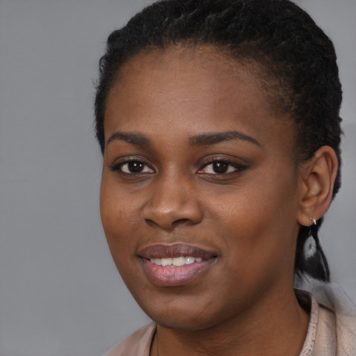 Joyful black young-adult female with long  brown hair and brown eyes