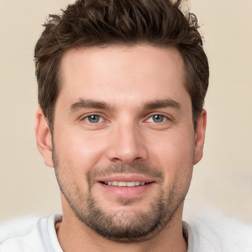 Joyful white young-adult male with short  brown hair and grey eyes