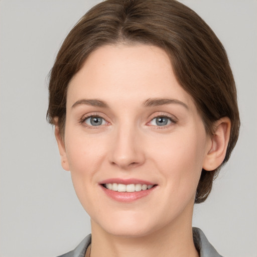 Joyful white young-adult female with medium  brown hair and grey eyes