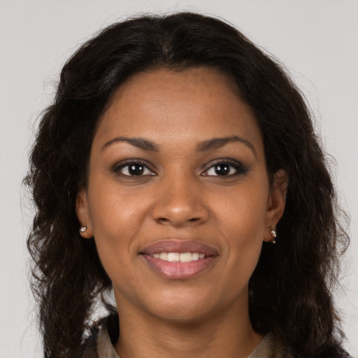 Joyful black young-adult female with long  brown hair and brown eyes