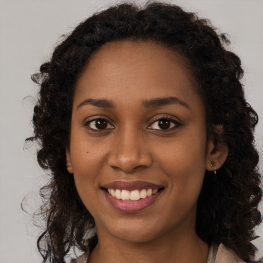 Joyful black young-adult female with long  brown hair and brown eyes