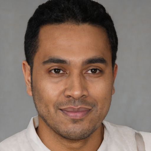 Joyful latino young-adult male with short  black hair and brown eyes