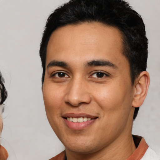 Joyful latino young-adult male with short  brown hair and brown eyes