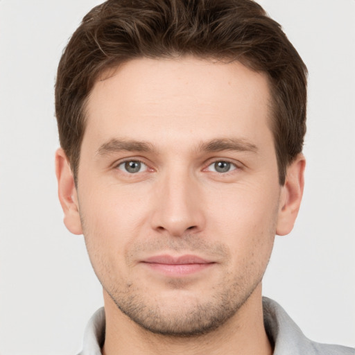 Joyful white young-adult male with short  brown hair and grey eyes