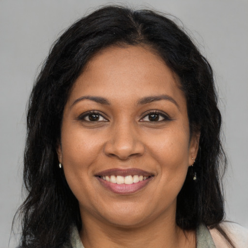 Joyful black adult female with long  brown hair and brown eyes