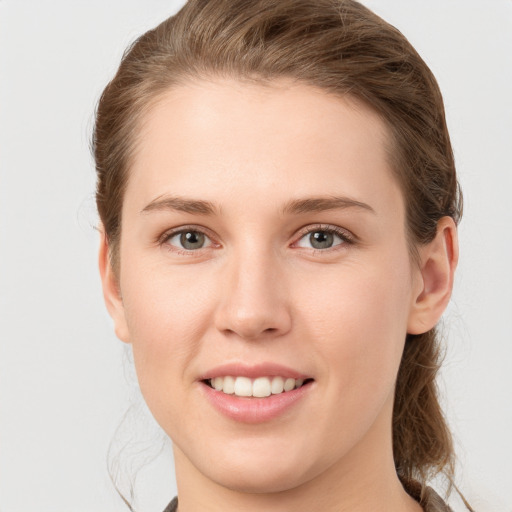 Joyful white young-adult female with medium  brown hair and grey eyes