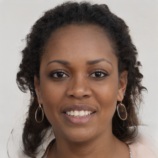 Joyful black young-adult female with long  brown hair and brown eyes