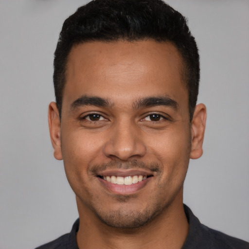 Joyful latino young-adult male with short  black hair and brown eyes