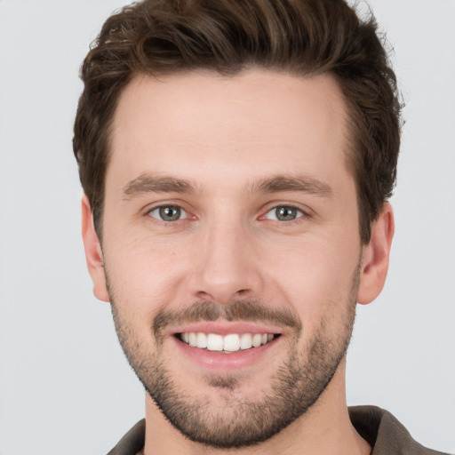 Joyful white young-adult male with short  brown hair and grey eyes