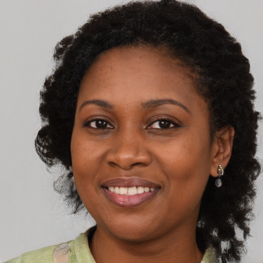 Joyful black young-adult female with long  black hair and brown eyes