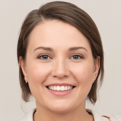 Joyful white young-adult female with medium  brown hair and grey eyes