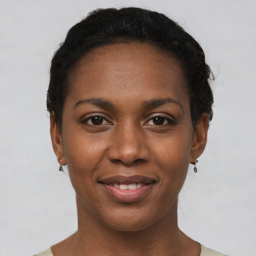 Joyful black young-adult female with short  black hair and brown eyes