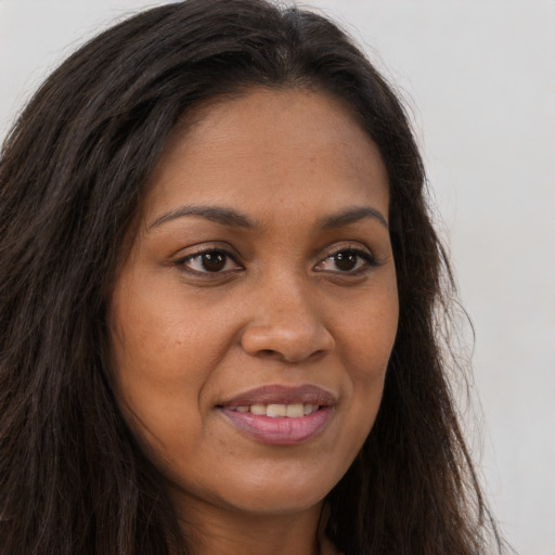 Joyful black young-adult female with long  brown hair and brown eyes