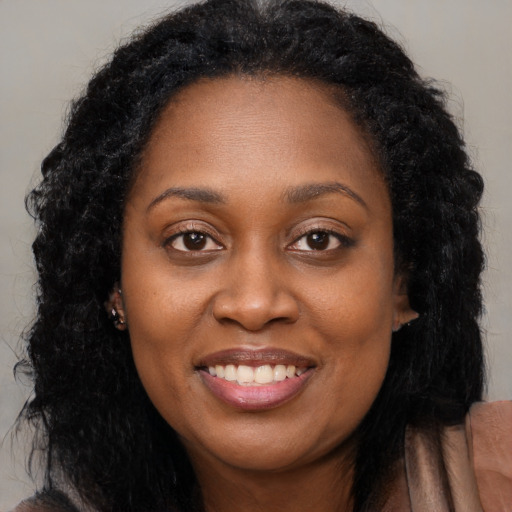 Joyful black adult female with long  brown hair and brown eyes