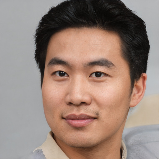 Joyful asian young-adult male with short  black hair and brown eyes