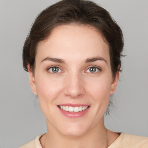 Joyful white young-adult female with medium  brown hair and grey eyes