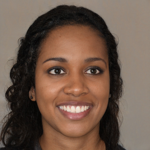 Joyful black young-adult female with long  brown hair and brown eyes