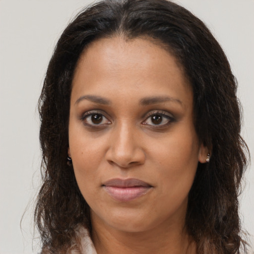 Joyful black young-adult female with long  brown hair and brown eyes