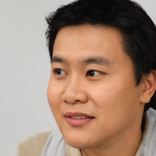 Joyful asian young-adult male with short  black hair and brown eyes