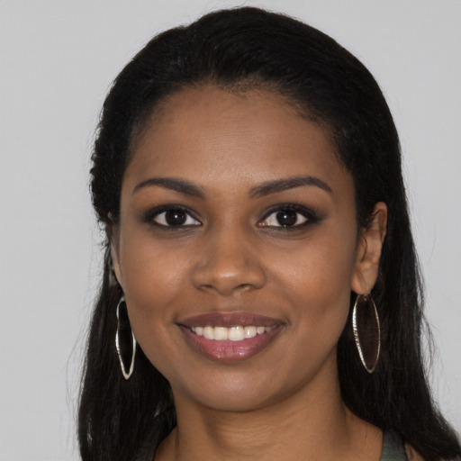 Joyful black young-adult female with long  black hair and brown eyes