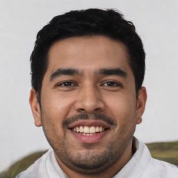 Joyful latino young-adult male with short  black hair and brown eyes