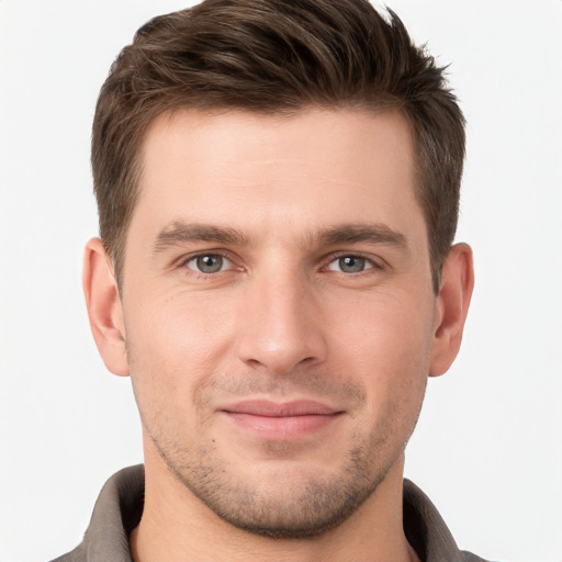 Joyful white young-adult male with short  brown hair and grey eyes