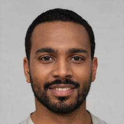 Joyful black young-adult male with short  black hair and brown eyes