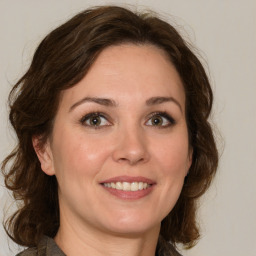 Joyful white adult female with medium  brown hair and green eyes